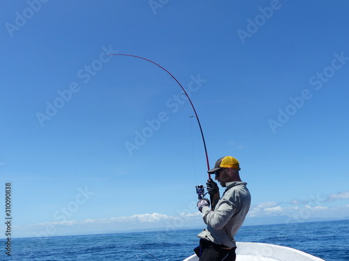 Fisherman fighting a fish with a blue sky background