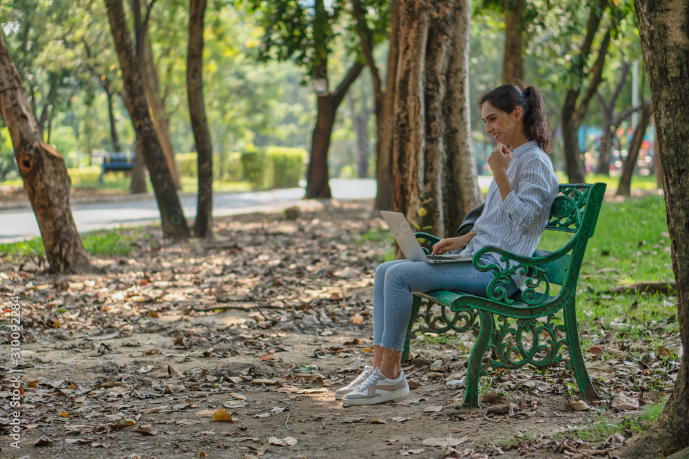 young caacasian university student or businesswoman sitting under tree in natural park using laptop computer for work young caacasian university student or businesswoman sitting under tree in natural park using laptop computer for work