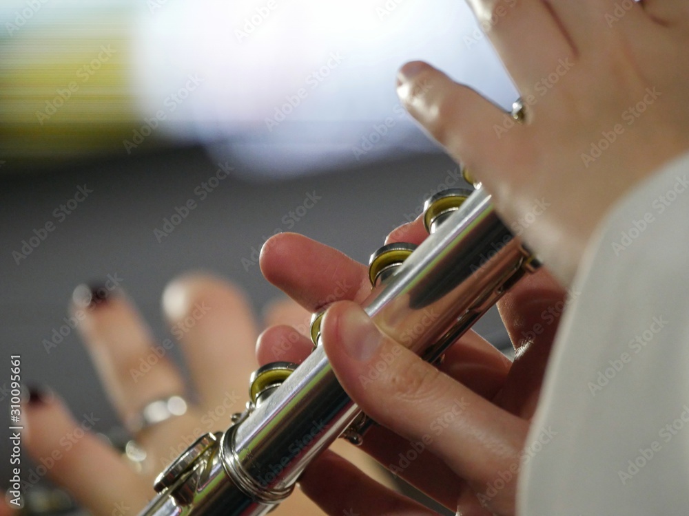 Obraz premium Hands playing notes on a flute, close up