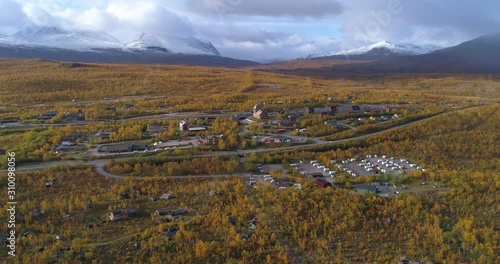 Abisko village in Lappland, aerial, tracking, drone shot, of a arctic town, in middle of autumn color nature, on a sunny fall day, in Lapland, Norrbotten, Sweden photo