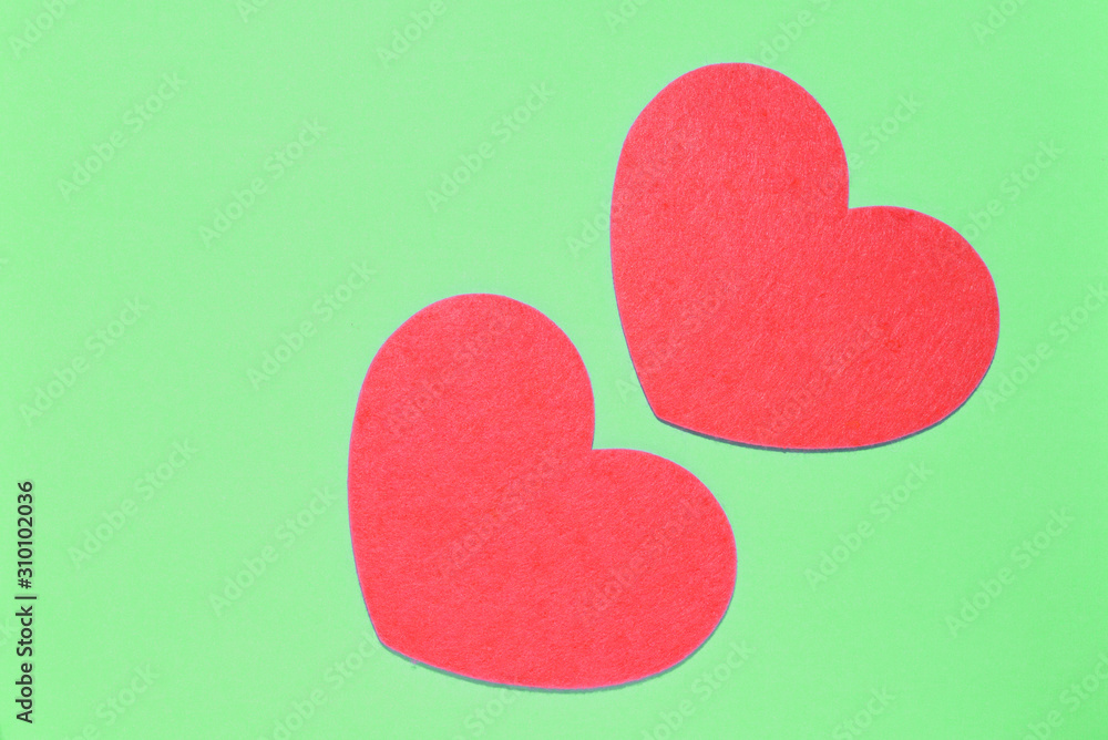Two red hearts on a light green background closeup. Greeting card with copy space. Valentine's Day concept
