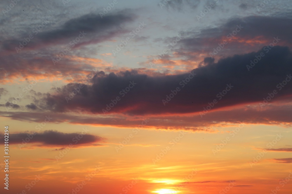 Beautiful orange sunset with dark burgundy clouds in the sky, natural background 