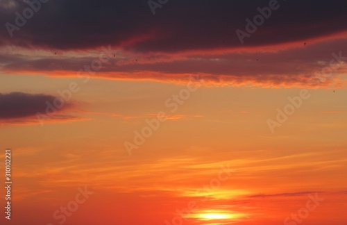 Beautiful fiery orange burgundy sunset with dark clouds, natural background