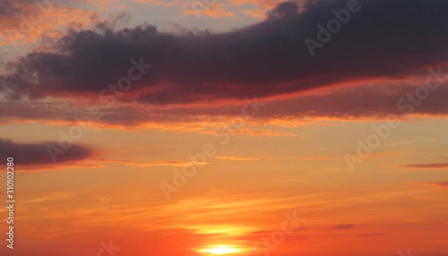 Beautiful orange fiery sunset over the city with burgundy clouds, natural background 