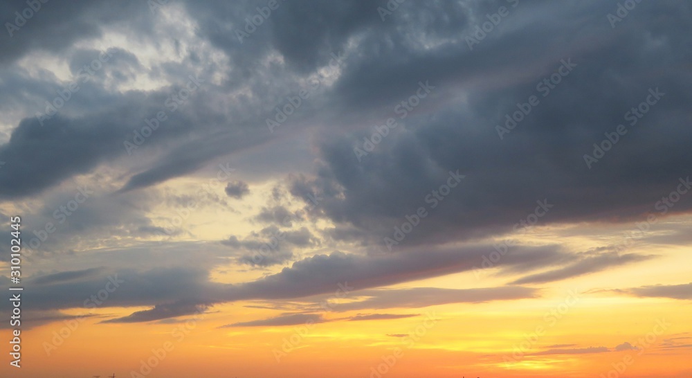 Beautiful yellow sunset background with black dramatic clouds