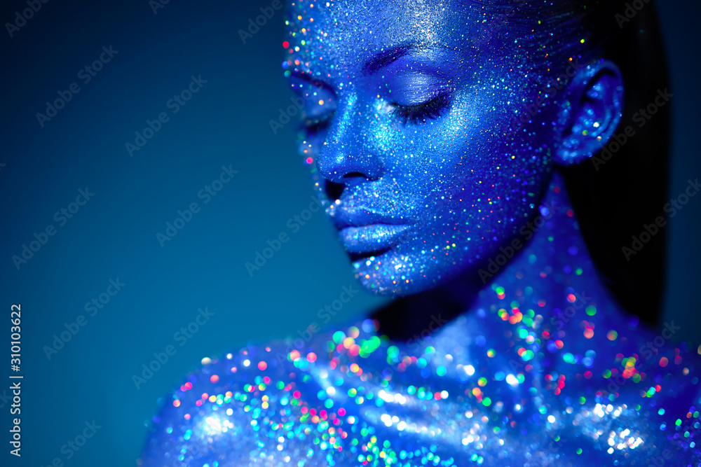Fashion model woman in blue bright sparkles and neon lights posing in studio. Portrait of beautiful sexy woman. Art design colorful glitter glowing make up Fashion model woman in blue bright sparkles and neon lights posing in studio. Portrait of beautiful sexy woman. Art design colorful glitter glowing make up