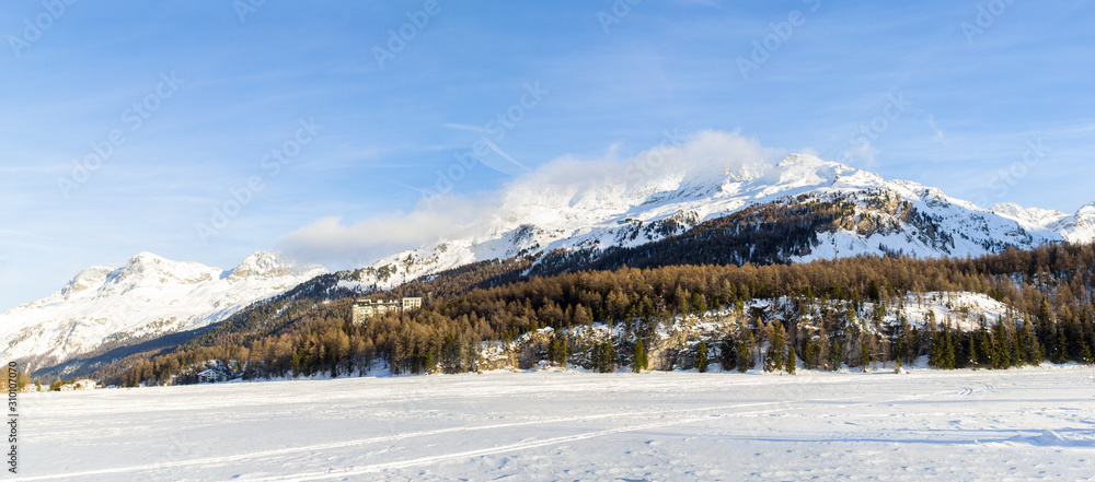St. Moritz, Switzerland - December 15. 2019: Snow field panorama in the famous recreation place St. Moritz with Hotel Waldhaus Sils over the mountain (large stiched file)