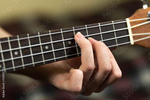 Hand holding a chord on the ukulele. Close up. Isolated on white background