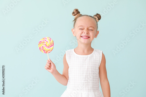 Fotografia Cute little girl with sweet lollipop on color background
