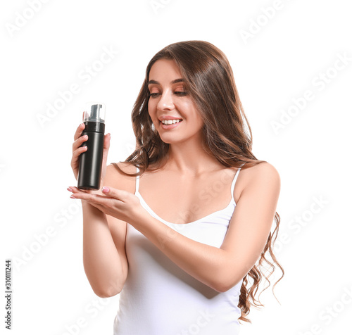 Beautiful young woman with bottle of cosmetics on white background
