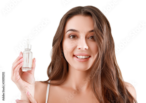 Beautiful young woman with bottle of serum on light background