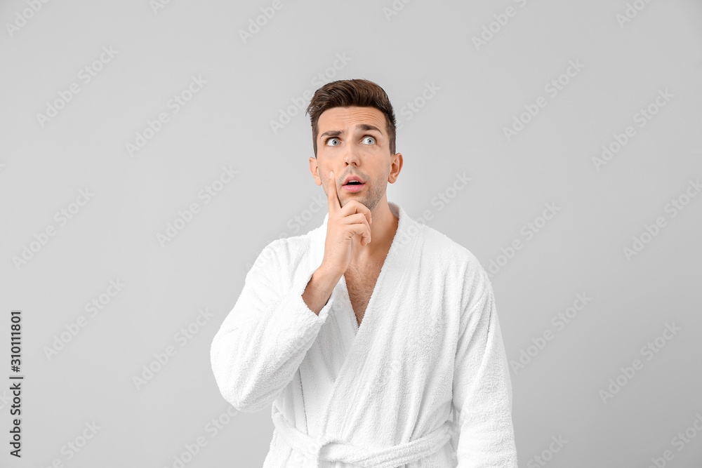 Surprised man in bathrobe on grey background