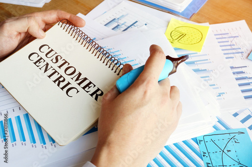 Man holds papers with Customer centric business conception. photo