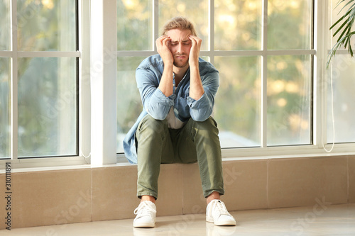 Depressed man near window a...