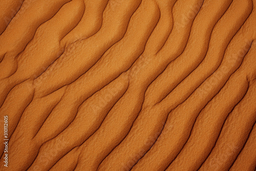 Wavy sandy texture on the dunes in the desert close-up. View from above
