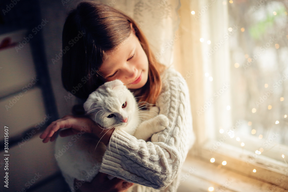 Caucasian kid girl in knitted dress holding cat Caucasian kid girl in knitted dress holding cat