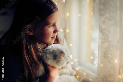 Caucasian kid girl in knitted dress holding cat