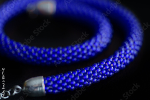 Bead crochet necklace blue color a dark surfce close up. Fashion background photo