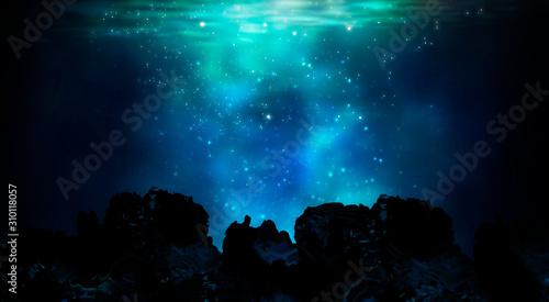 The depths of the sun through the water, the underwater world, the sea floor. Marine underwater landscape. Stones, corals, neon glow, reflection on the water. Night view. photo