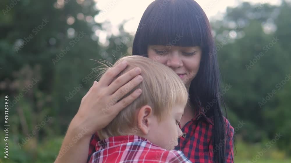 happy family mom and son concept lifestyle . mom tender childhood video . slow motion video . mom a brunette girl gently hugs takes care of the son boy blonde outdoors happy family mom and son concept lifestyle . mom tender childhood video . slow motion video . mom a brunette girl gently hugs takes care of the son boy blonde outdoors