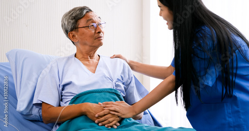 Female medical assistant taking care of adult patient at hospital room.