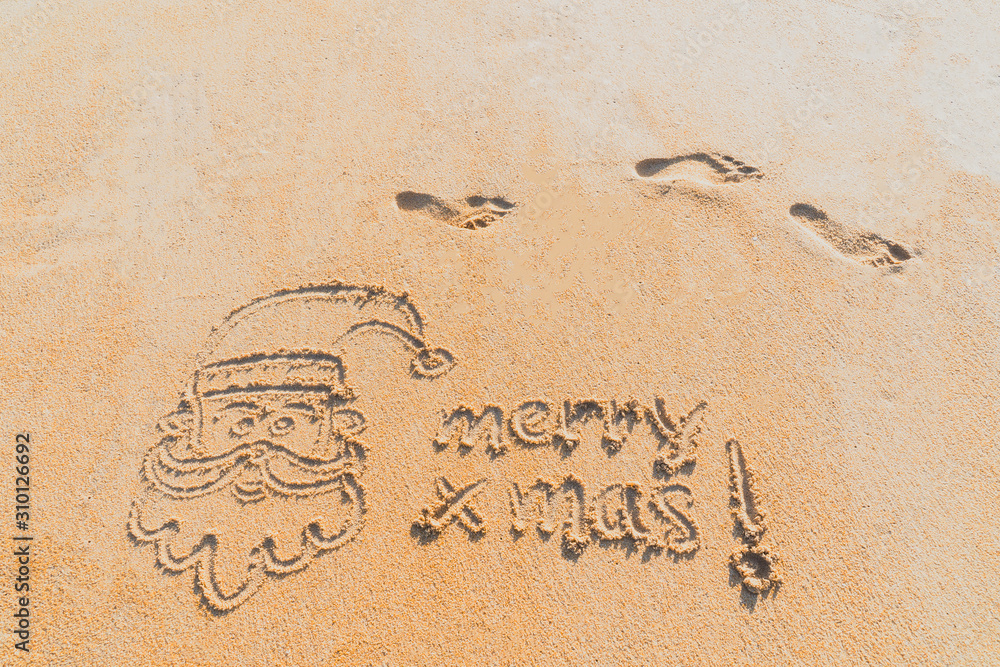Fototapeta premium Concept Christmas on the beach Tropical design made in Phuket, Thailand Write the alphabet on the sand background Taken from real locations.
