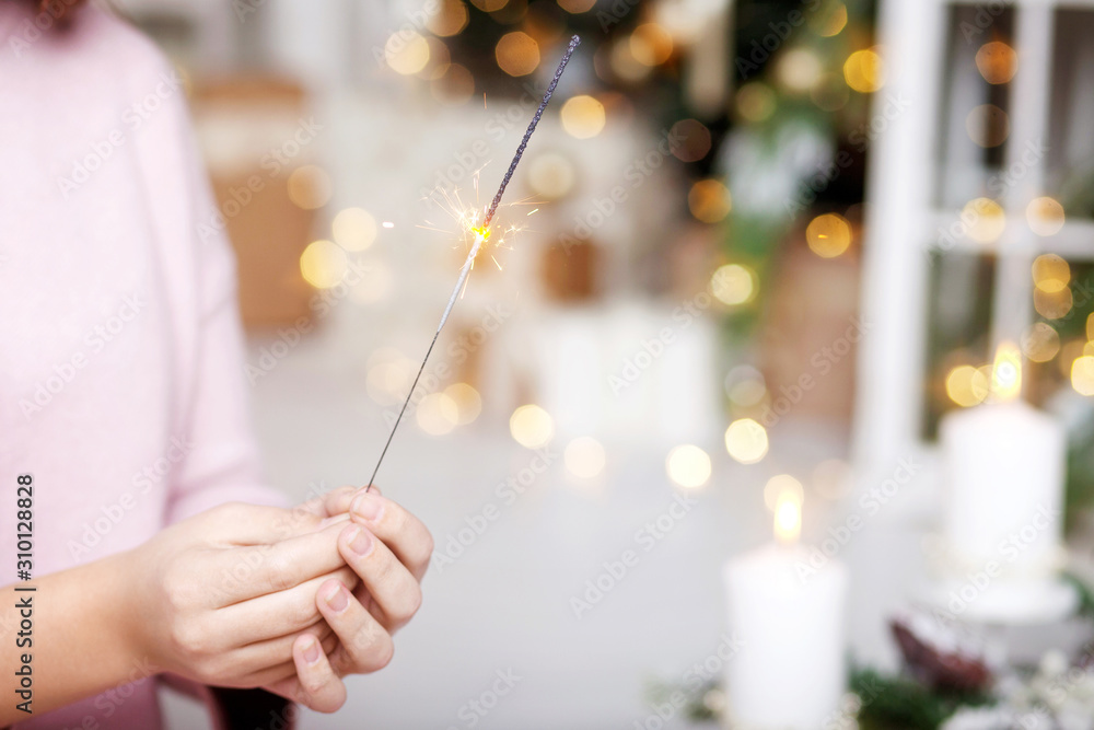 Fototapeta premium Close up of woman hands holding sparkler. New year party burning sparkler closeup in female hand. Christmas light