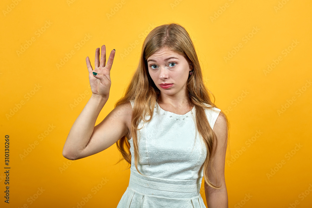 Charming blonde caucasian young woman showing four fingers, looking at camera over isolated orange background wearing white shirt. Lifestyle concept Charming blonde caucasian young woman showing four fingers, looking at camera over isolated orange background wearing white shirt. Lifestyle concept