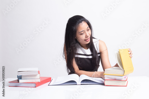 Young Asian woman read a book with books on table