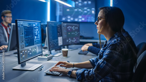 Smart Young Female IT Programer Working on Desktop Green Mock-up Screen Computer in Data Center System Control Room. Team of Young Professionals Programming Sophisticated Code photo