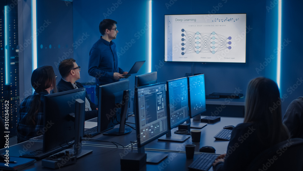 Team of Professional IT Developers Have Meeting, Speaker Talks about New Blockchain Based Software Development Shown on TV. Concept: Deep Learning, Artificial Intelligence, Data Mining, Neural Network Team of Professional IT Developers Have Meeting, Speaker Talks about New Blockchain Based Software Development Shown on TV. Concept: Deep Learning, Artificial Intelligence, Data Mining, Neural Network