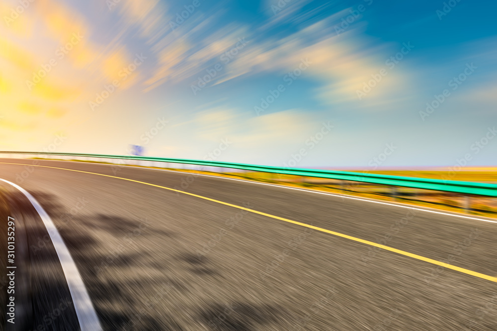 Fototapeta premium Blurred moving asphalt road and colorful sky at sunset