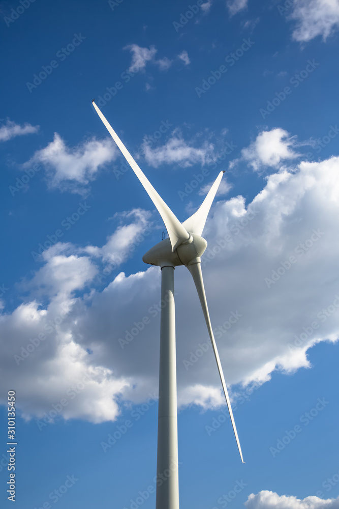 View of a wind turbine on top of mountains, cloudy sky as background View of a wind turbine on top of mountains, cloudy sky as background