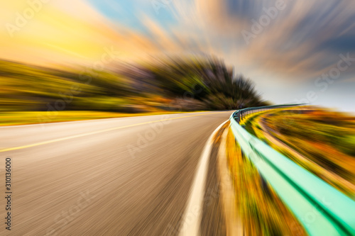Blurred moving asphalt road and colorful sky at sunset