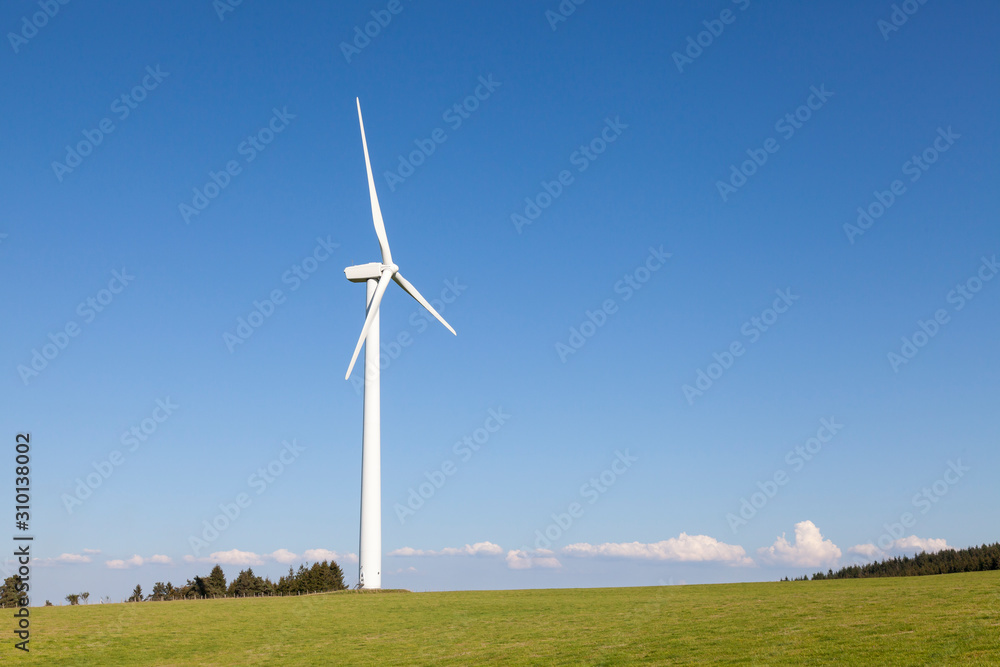 Single wind turbine in a lush green hilltop pasture providing green renewable energy Single wind turbine in a lush green hilltop pasture providing green renewable energy