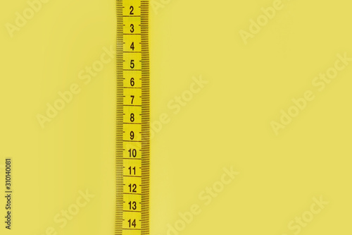 close up of measure tape on yellow background 