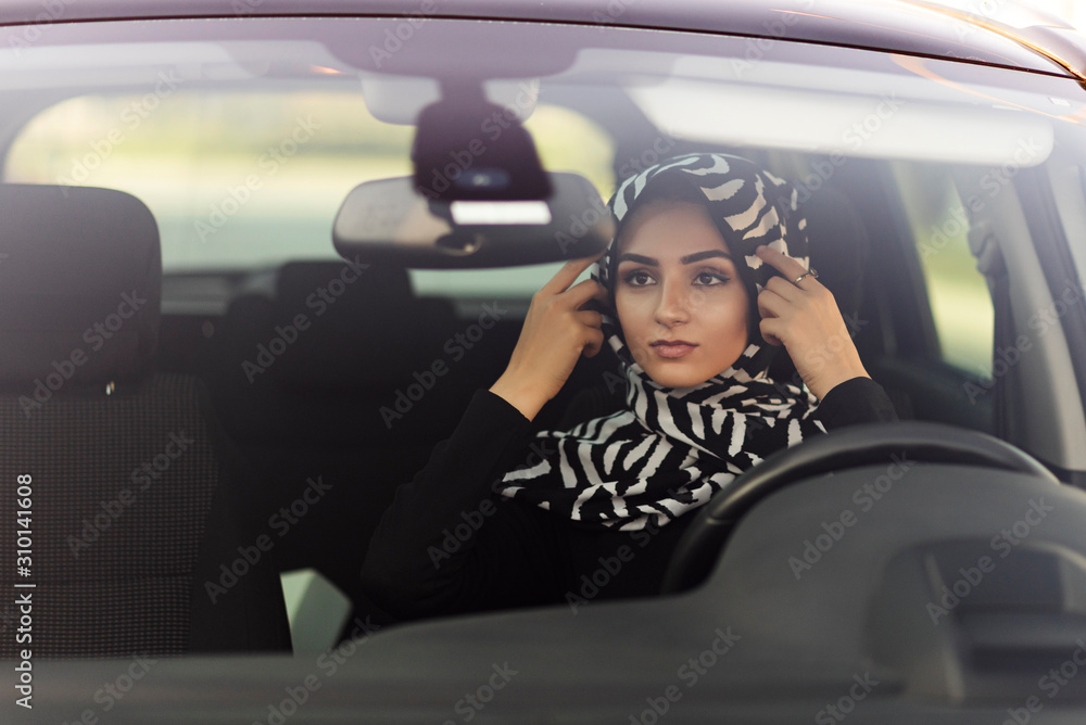 muslim young woman straightens headscarf in car muslim young woman straightens headscarf in car