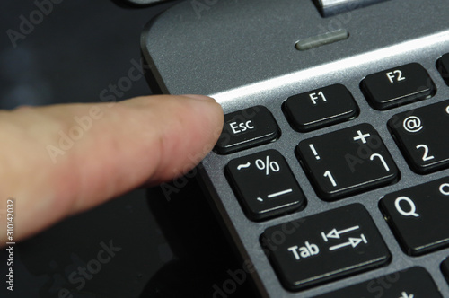 Finger is hitting escape button of computer keyboard.