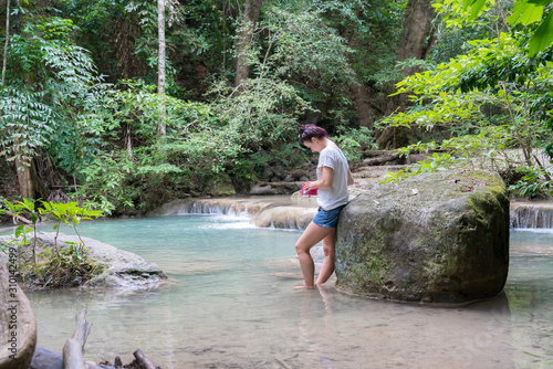 young cute hipster girl travelling at beautiful Erawan waterfall mountains  green forest hiking views at Kanchanaburi, Thailand. guiding  idea for female backpacker woman women backpacking