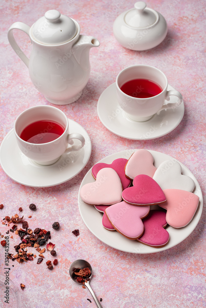 Heart shape cookies with icing with berry tea. Concept: Valentine's Day tea party, festive table setting in pink. Heart shape cookies with icing with berry tea. Concept: Valentine's Day tea party, festive table setting in pink.
