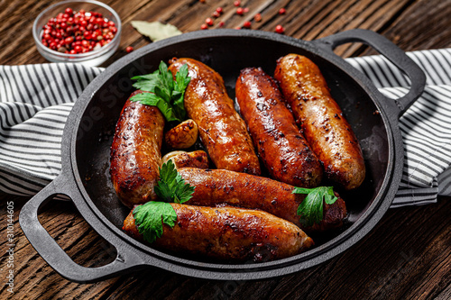 The concept of farm, organic products. Homemade grilled pork barbecue sausages in an iron pan. background image. copy space