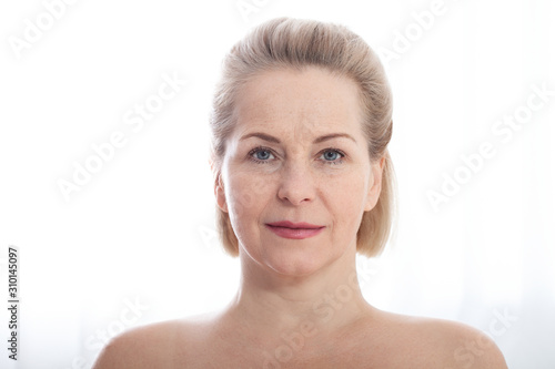 Beautiful middle-aged woman fase close up on white background. Skin care for wrinkled face  anti-aging facelift treatment. Facial skincare and contouring. Beauty and make-up