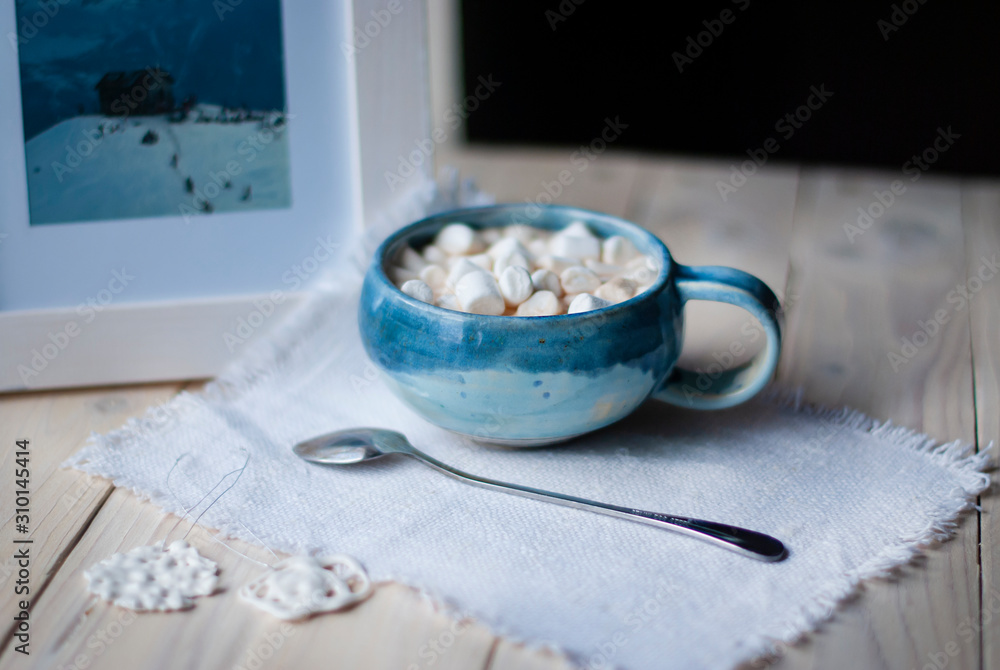 A cup of cacao with marshmellows and christmas decoration on the table with colorful background. Chistmas holiday background. Phantom Blue. A cup of cacao with marshmellows and christmas decoration on the table with colorful background. Chistmas holiday background. Phantom Blue.