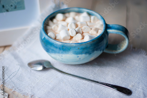 A cup of cacao with marshmellows and christmas decoration on the table with colorful background. Chistmas holiday background. Phantom Blue.