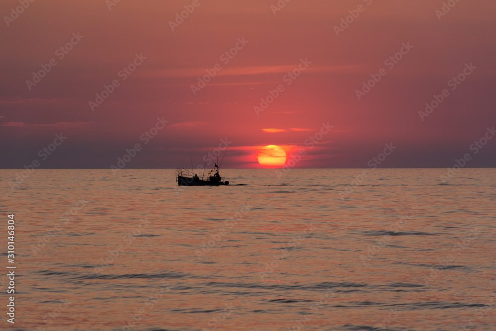 Beautiful sunset on the sea with fishermen boat Beautiful sunset on the sea with fishermen boat