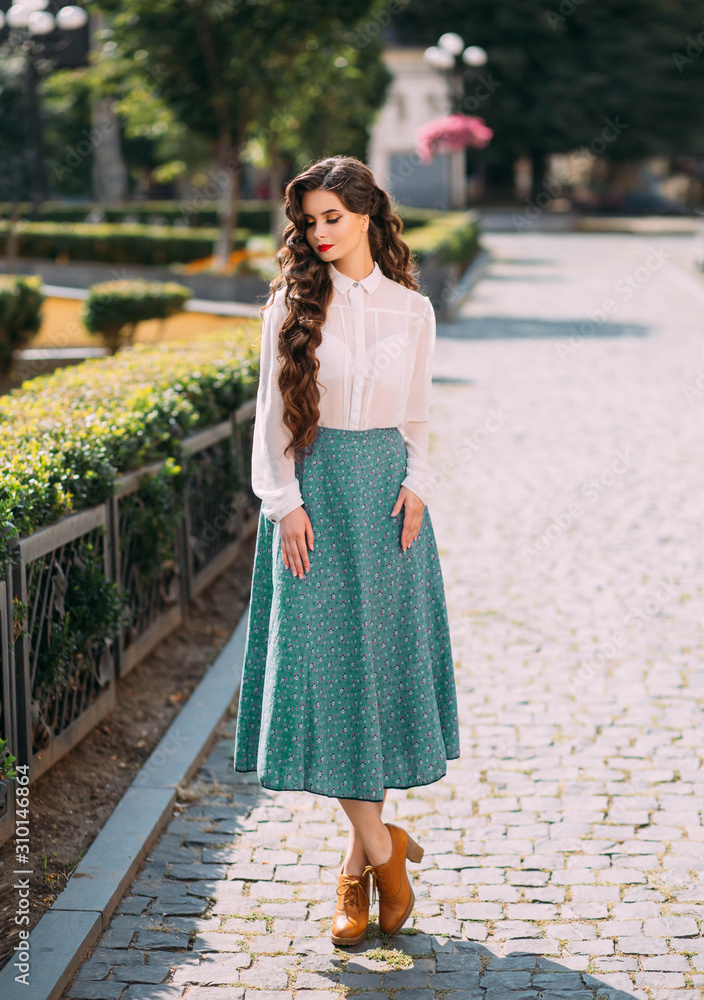 portrait brunette Parisian woman long healthy hair. hairstyle curls waves Hollywood retro style. White vintage silk blouse mint midi elegance skirt. urban sunny day green street trees. outfit stylish
