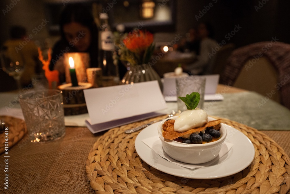 creme brulee with blueberries and ice cream on table in fancy restaurant