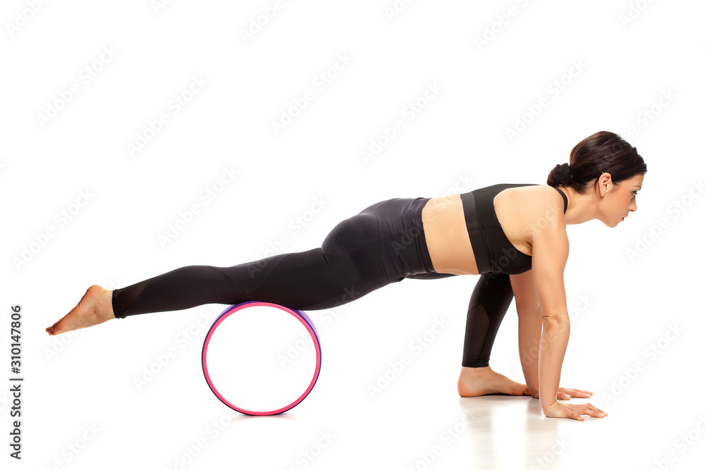 Young beautiful fit yoga woman with a fitness wheel, isolated on white background.