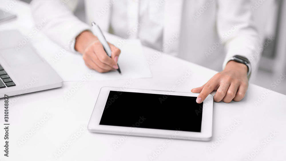 Cropped photo of girl using touchpad taking notes Cropped photo of girl using touchpad taking notes