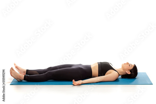 Young fit yoga woman resting on her mat, isolated on white background.